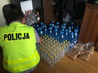 Policjant liczy butelki z przeźroczystym płynem - alkoholem