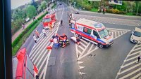 Miejsce wypadku drogowego, widzimy udzielajacych pomocy rannemu motocykliści. Widać pojazdy pogotowia i straży pożarnej