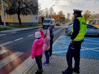 Policjant przeprowadza dzieci przez jezdnię