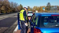 Policjant drogówki kontroluje kierowcę niebieskiej osobówki
