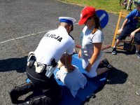 Policjant udziela instruktażu dziecku - jak prowadzić masaż serca
