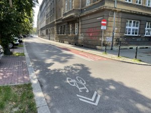 Ulica z wyznaczonym kontrapasem rowerowym i strzałkami namalowanymi na asfalcie informującymi o kontraruchu.