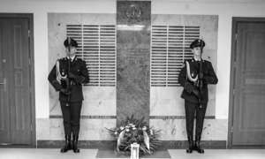 Na zdjęciu warta honorowa - dwóch policjantów stoi na baczność przy tablicy upamiętniającej poległych w słuzbie.